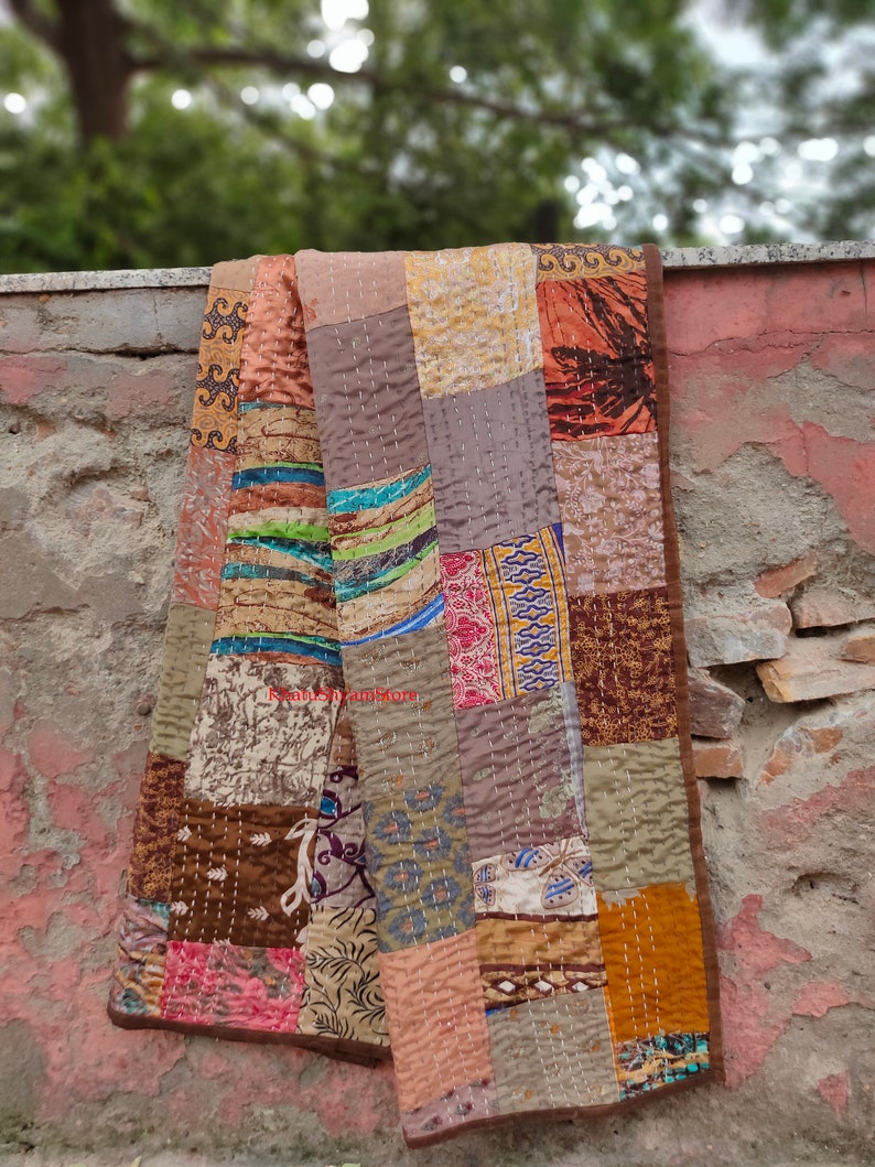 May include: A patchwork quilt made from repurposed fabric scraps in shades of brown, beige, and orange. The quilt is hand-stitched and has a rustic, vintage look.