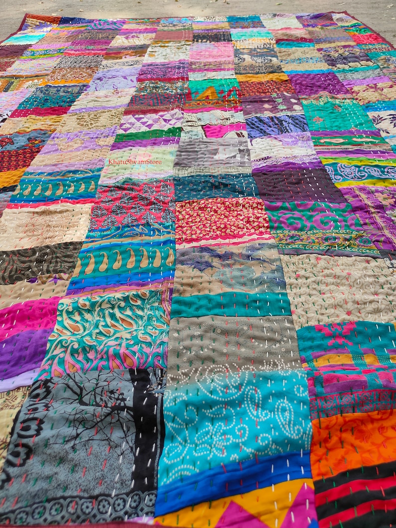 May include: A colorful patchwork quilt made from a variety of fabrics. The quilt is made up of squares of different colors and patterns, including floral, paisley, and geometric designs. The quilt is hand-stitched and has a rustic, vintage look.