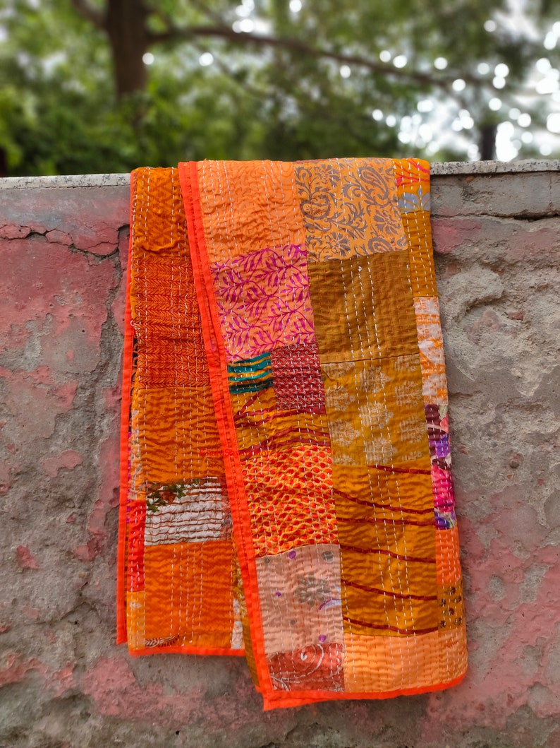 May include: A patchwork quilt with a variety of orange, brown, and pink fabrics. The quilt is hand-stitched and has a unique, rustic look.