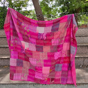 Puede incluir: Una colcha de retazos rosa con una variedad de patrones y texturas. La colcha está hecha de muchas telas diferentes, incluyendo seda, algodón y terciopelo. Es una obra de arte hermosa y única.