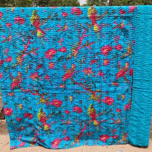 May include: A blue kantha quilt with a floral and bird pattern. The quilt is made of cotton and is hand-stitched. It is a traditional Indian textile.