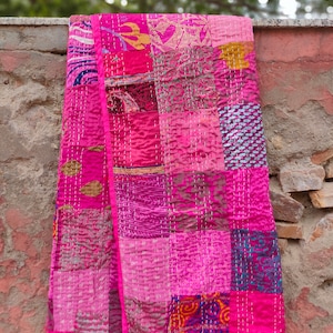 May include: A pink patchwork quilt made from various fabrics with a quilted design. The quilt is made up of squares of different colors and patterns, including floral, paisley, and geometric designs.