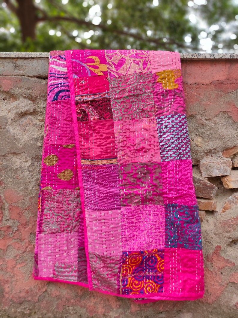 May include: A pink patchwork quilt made from various fabrics with a quilted design. The quilt is made up of squares of different colors and patterns, including floral, paisley, and geometric designs.