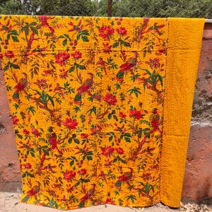 May include: A yellow kantha quilt with a floral and bird pattern. The quilt is made of cotton and is hand-stitched. It is a traditional Indian textile.