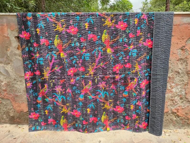 May include: Black kantha quilt with a floral and bird pattern. The quilt is made of cotton and has a hand-stitched design.
