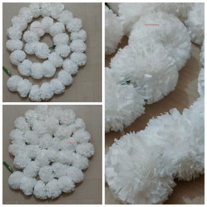 May include: White artificial flower garland made of paper. The garland is arranged in a circle and is made up of many small, fluffy white flowers.