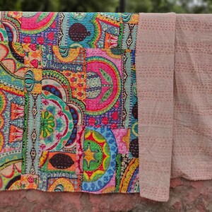 Puede incluir: Una colcha kantha colorida con un dise&ntilde;o de patchwork que presenta formas geom&eacute;tricas y motivos florales. La colcha est&aacute; hecha de algod&oacute;n y tiene un respaldo beige.