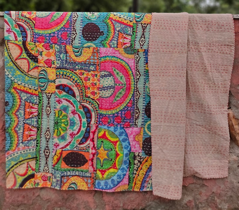 Puede incluir: Una colcha kantha colorida con un dise&ntilde;o de patchwork que presenta formas geom&eacute;tricas y motivos florales. La colcha est&aacute; hecha de algod&oacute;n y tiene un respaldo beige.