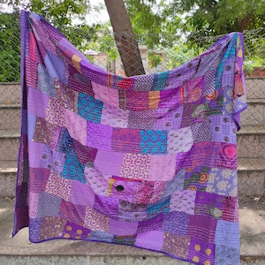May include: A purple patchwork quilt with a variety of patterns and textures. The quilt is made of many different pieces of fabric sewn together, creating a unique and colorful design.