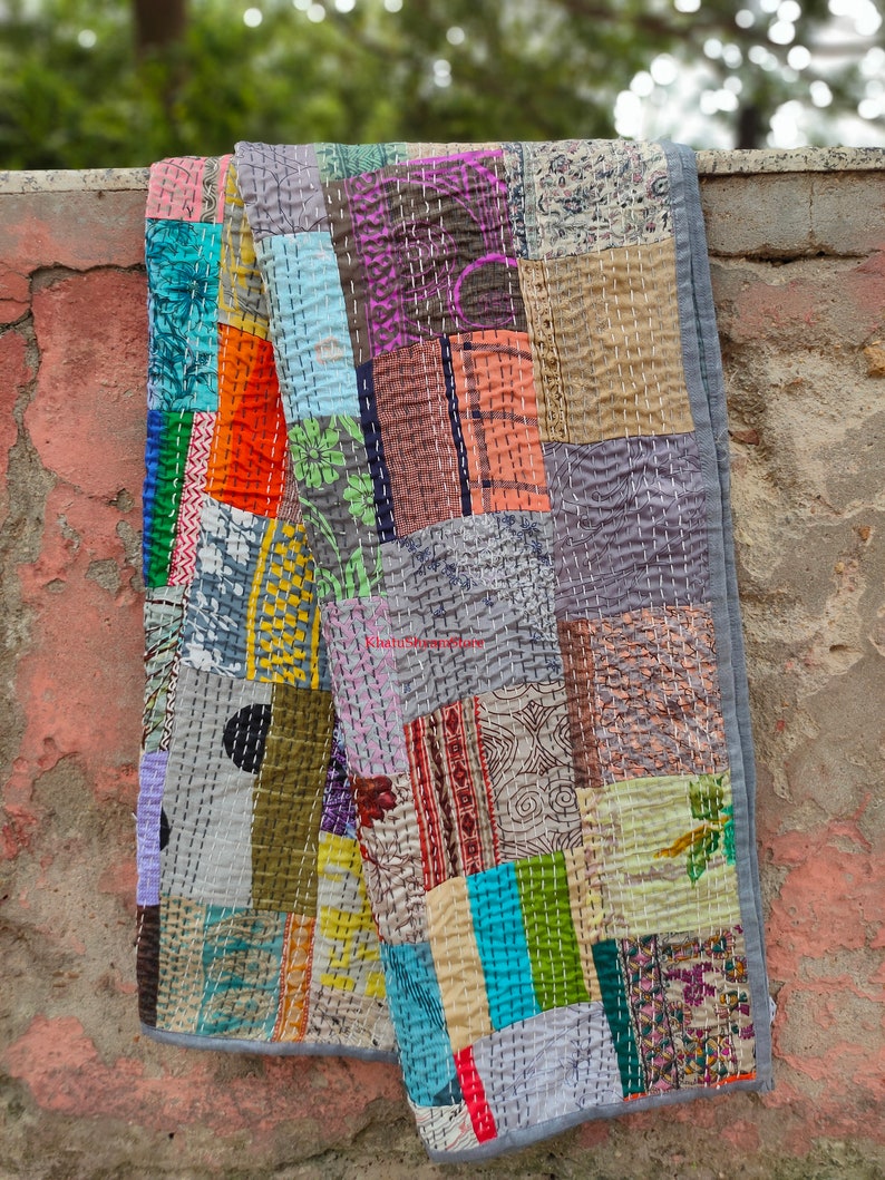 May include: A patchwork quilt made from a variety of colorful fabrics, including floral prints, stripes, and geometric patterns. The quilt is hand-stitched and has a rustic, vintage look.