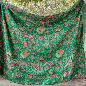 K&ouml;nnte beinhalten: Eine gr&uuml;ne Kantha-Steppdecke mit einem floralen Muster in Rosa-, Gelb- und Blaut&ouml;nen. Die Steppdecke ist aus Baumwolle und handgen&auml;ht.