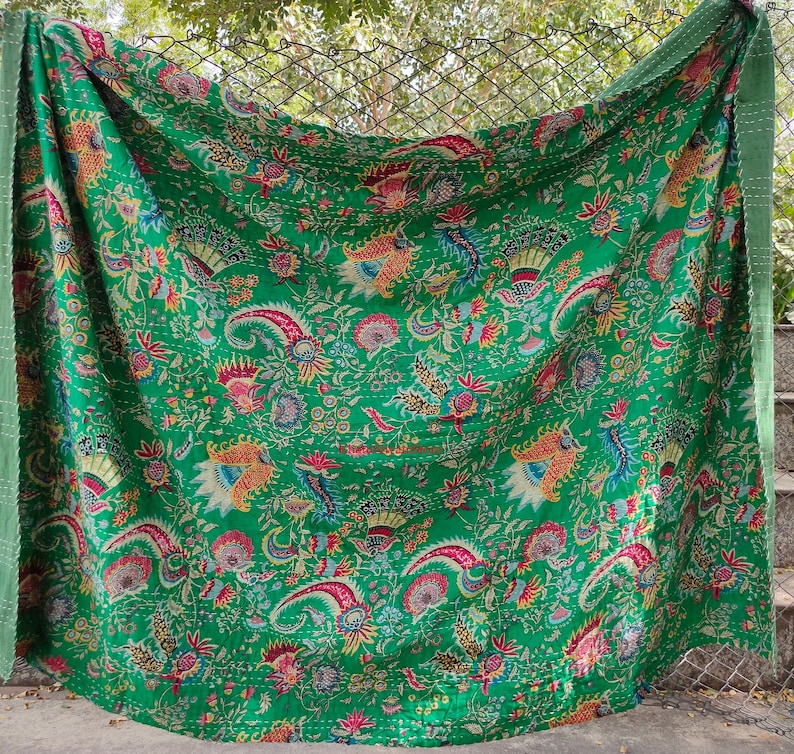 K&ouml;nnte beinhalten: Eine gr&uuml;ne Kantha-Steppdecke mit einem floralen Muster in Rosa-, Gelb- und Blaut&ouml;nen. Die Steppdecke ist aus Baumwolle und handgen&auml;ht.