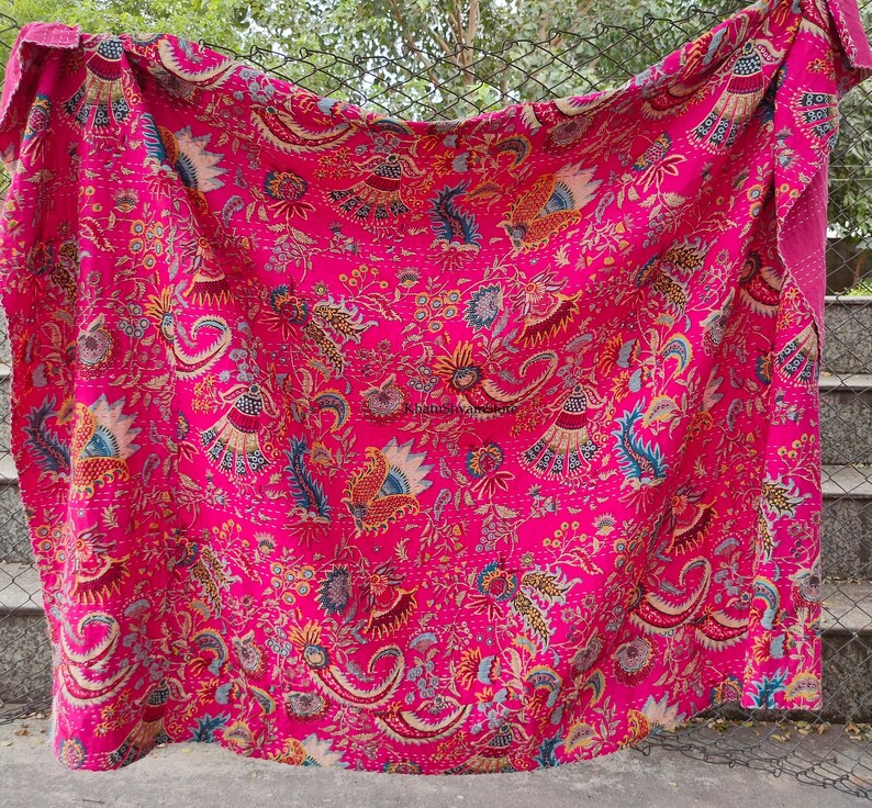 K&ouml;nnte beinhalten: Eine rosafarbene Kantha-Steppdecke mit floralem und Paisley-Muster. Die Decke ist aus Baumwolle und handgen&auml;ht.