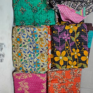 Könnte beinhalten: Sechs Kantha-Steppdecken in verschiedenen Blumenmustern. Die Decken sind aus recycelten Saris hergestellt und handgenäht. Die Decken sind in den Farben Grün, Braun, Rosa, Orange und Schwarz gehalten. Die Decken sind gefaltet und übereinander gestapelt. Der Text "Khatushyamstore" ist auf den Decken sichtbar.