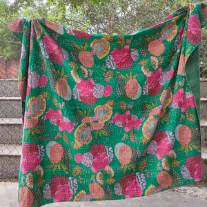 Op de afbeelding: Een groene kantha-deken met een bloemen- en ananaspatroon. De deken is gemaakt van katoen en met de hand gestikt.