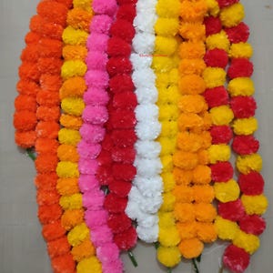 May include: A collection of colorful marigold garlands in shades of orange, yellow, pink, red, and white. The garlands are arranged vertically, showcasing the vibrant colors and textures of the flowers. The image is well-lit, highlighting the details of each flower.