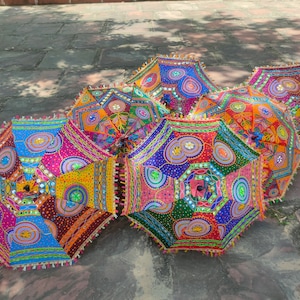 May include: Five colorful umbrellas with intricate embroidery and mirror embellishments. The umbrellas are made of fabric and have a traditional Indian design.
