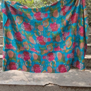 Op de afbeelding: Een turquoise blauwe kantha-deken met een bloemen- en ananaspatroon. De deken is gemaakt van katoen en heeft een handgestikt ontwerp.