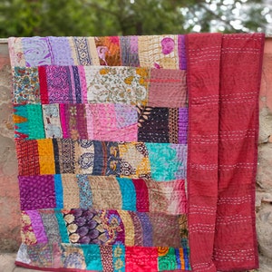 May include: A patchwork quilt made from colorful fabric scraps. The quilt is a mix of floral, geometric, and abstract patterns. The quilt is hand-stitched and has a rustic, vintage look.