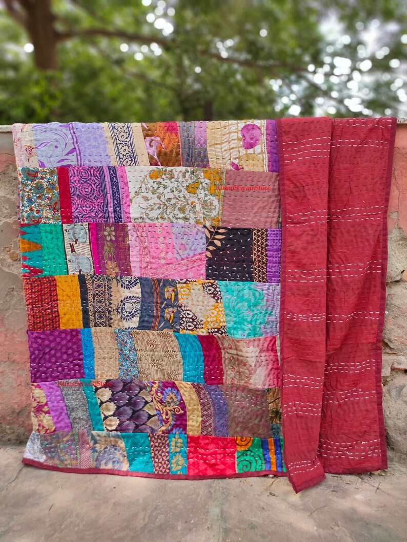 May include: A patchwork quilt made from colorful fabric scraps. The quilt is a mix of floral, geometric, and abstract patterns. The quilt is hand-stitched and has a rustic, vintage look.