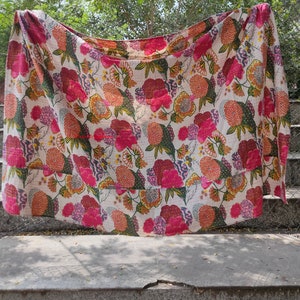 Op de afbeelding: Een wit kantha-dekbed met een bloemenpatroon in tinten roze, oranje en groen. Het dekbed is gemaakt van katoen en met de hand gestikt.