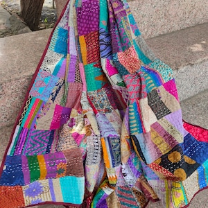 Può includere: Una trapunta colorata a patchwork realizzata con tessuti riutilizzati. La trapunta è composta da una varietà di colori e motivi, tra cui floreali, geometrici e paisley. La trapunta è cucita a mano e ha un aspetto vintage unico.