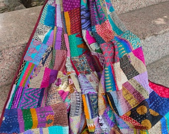 May include: A colorful patchwork quilt made from repurposed fabrics. The quilt is made up of a variety of colors and patterns, including floral, geometric, and paisley. The quilt is hand-stitched and has a unique, vintage look.