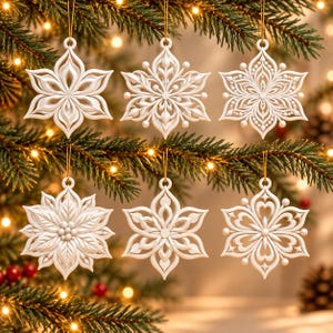 May include: A set of six white, intricate snowflake-shaped ornaments hanging from thin gold strings. Each ornament features a unique, symmetrical, laser-cut design with detailed patterns, including floral-like petals, dots, and geometric shapes.