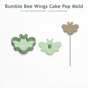 以下が含まれることがあります： 「Bumble Bee Wings Cake Pop Mold」と「STL FILE FOR 3D PRINTING - DIGITAL DOWNLOAD」の文字が入った、薄緑色のハチの羽のケーキポップ型。型は2つのパーツと完成したケーキポップで構成されています。