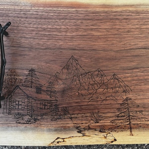 Tabla de servir de madera de nogal negro con paisaje de montaña y cabaña quemado a mano