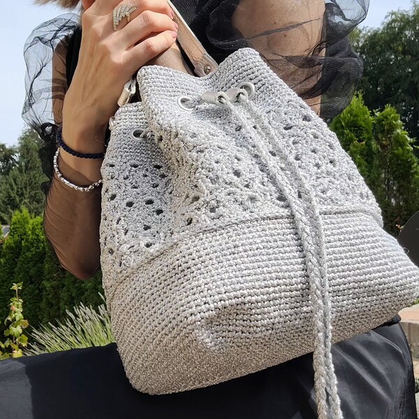 A crochet bag with a floral pattern made from metallic yarn. Evening bag.