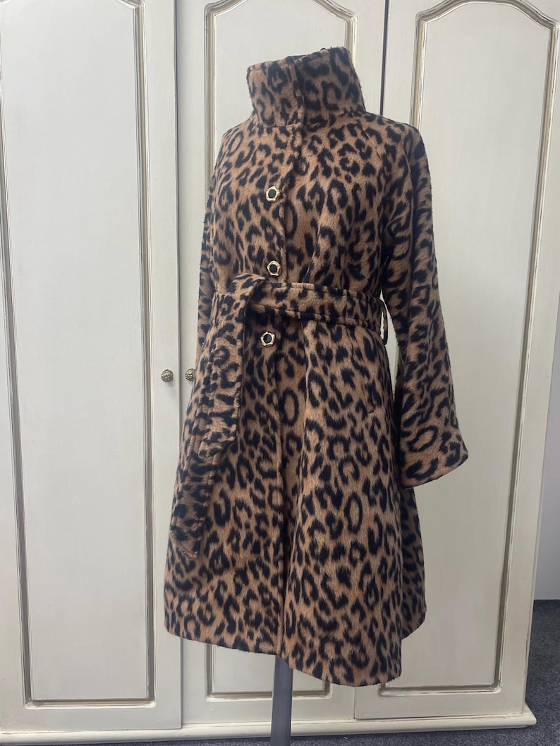 May include: A brown and black leopard print coat with a high collar, a belt, and gold buttons.