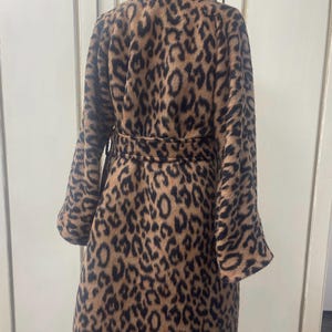 May include: A brown and black leopard print coat with a high collar and a belt. The coat has long sleeves and a fitted silhouette.