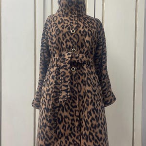 May include: A brown and black leopard print coat with a high collar, a belt, and gold buttons.