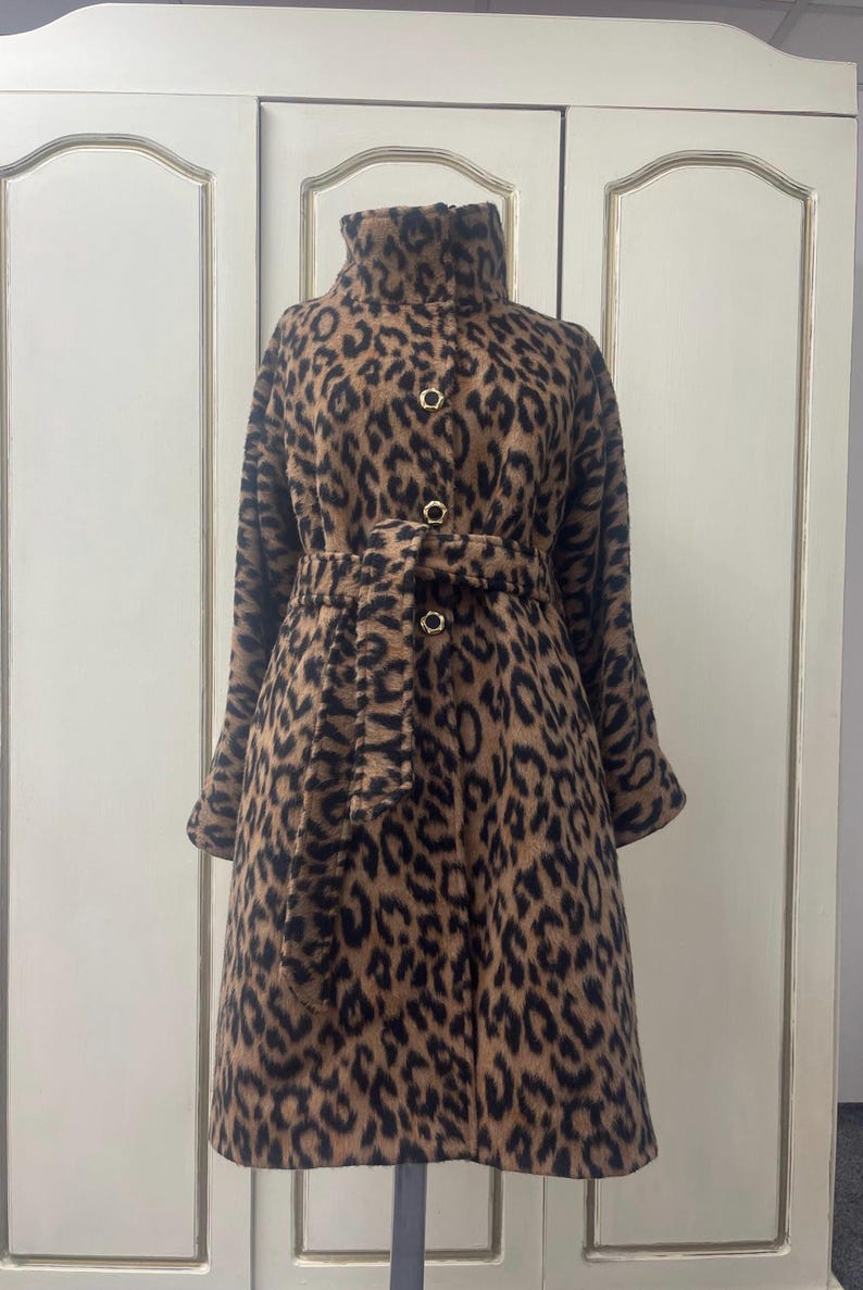 May include: A brown and black leopard print coat with a high collar, a belt, and gold buttons.