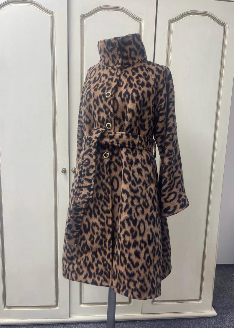 May include: A brown and black leopard print coat with a high collar, a belt, and gold buttons.