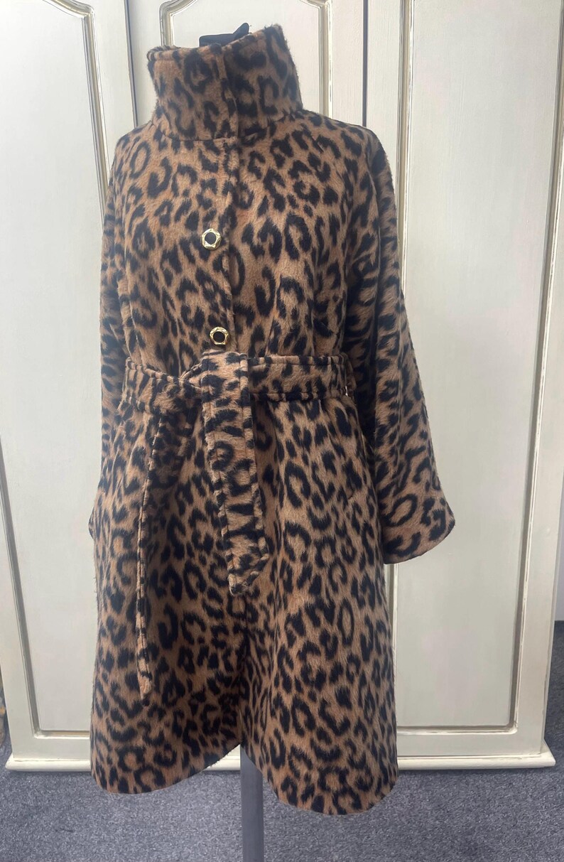 May include: A brown and black leopard print coat with a high collar, a belt, and gold buttons.