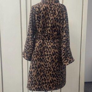 May include: A brown and black leopard print coat with a high collar and a belt. The coat is made of a soft, fuzzy material.