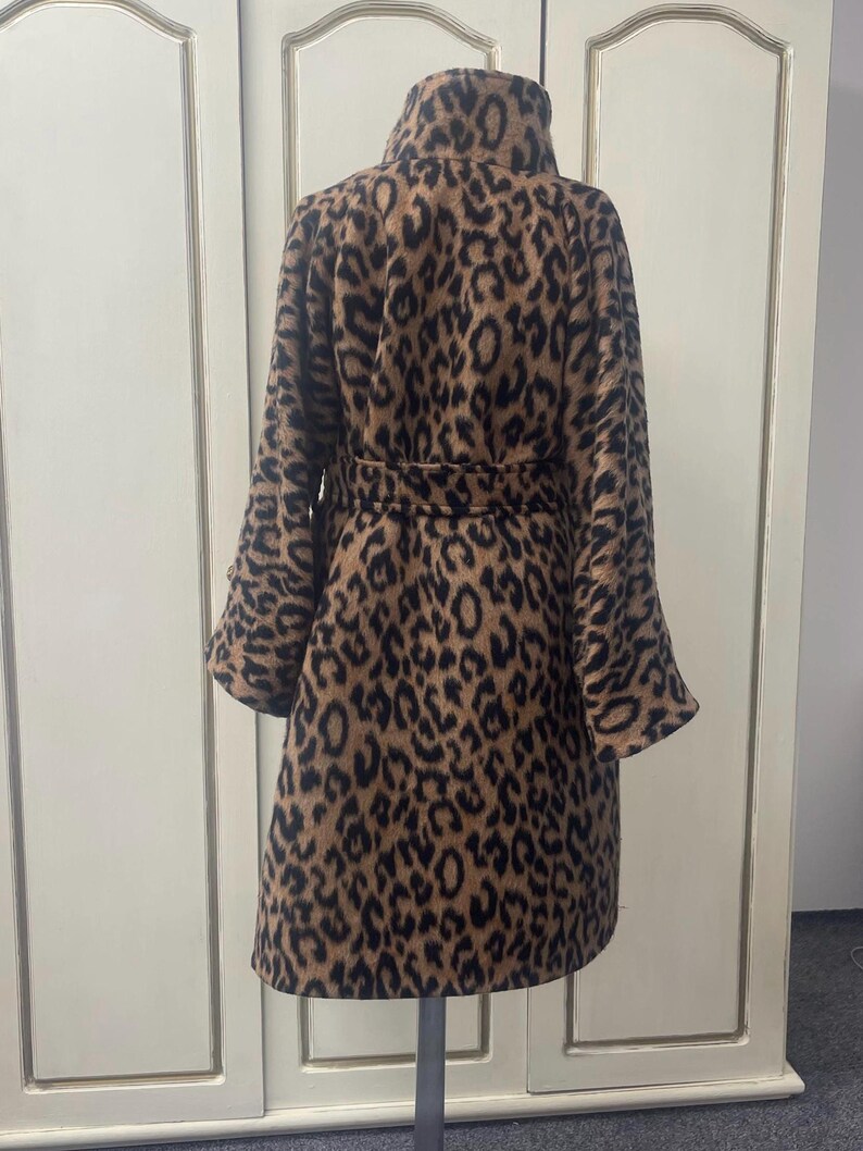 May include: A brown and black leopard print coat with a high collar and a belt. The coat is made of a soft, fuzzy material.