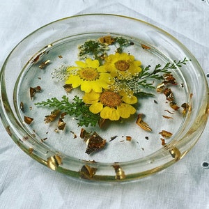 May include: A clear glass coaster with a resin design of yellow flowers and gold leaf accents.