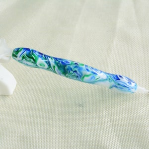 May include: A blue, green, and white marbled diamond painting pen with a clear tip.