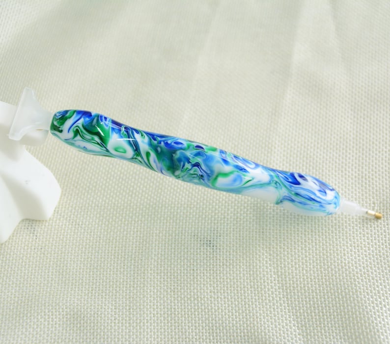 May include: A blue, green, and white marbled diamond painting pen with a clear tip.