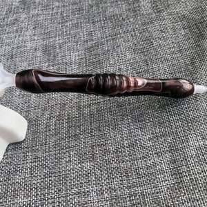 May include: A black and white diamond painting pen with a clear plastic tip. The pen has a swirl pattern.