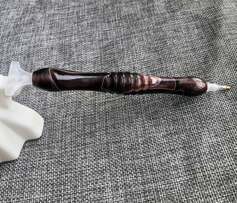 May include: A black and white diamond painting pen with a clear plastic tip. The pen has a swirl pattern.