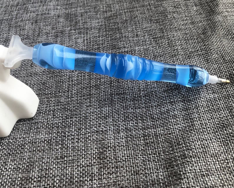 May include: A blue and white diamond painting pen with a clear plastic handle and a pointed tip.