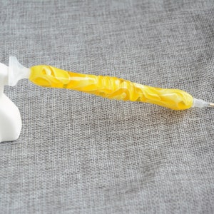 May include: A yellow diamond painting pen with a clear plastic handle and a pointed tip.