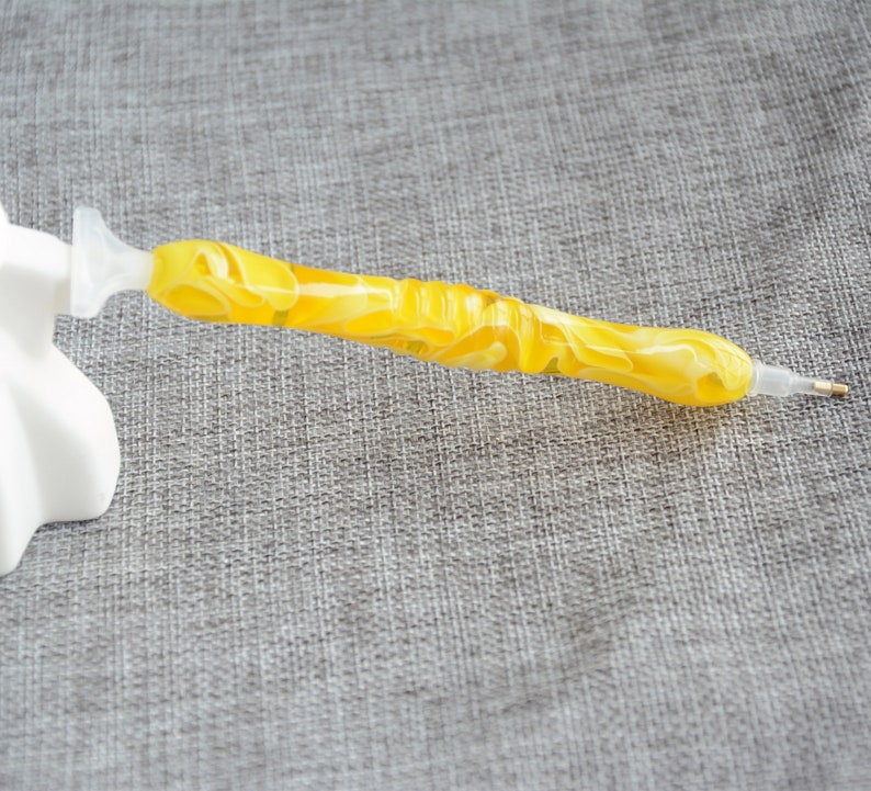 May include: A yellow diamond painting pen with a clear plastic handle and a pointed tip.