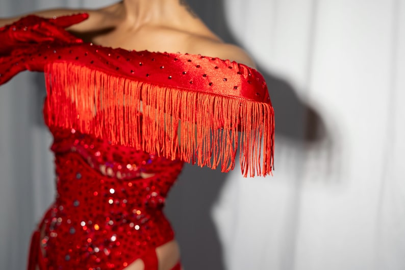 Peut inclure: Une tenue de danse rouge &agrave; paillettes avec un d&eacute;collet&eacute; &agrave; franges et des gants assortis.