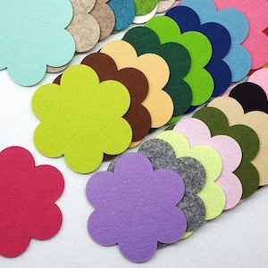 Könnte beinhalten: Ein Stapel Filz-Untersetzer in Blumenform in verschiedenen Farben, darunter Grün, Blau, Rosa, Rot und Braun. Die Untersetzer sind fächerförmig angeordnet, wobei der oberste Untersetzer hellblau ist.
