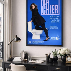Puede incluir: Un p&oacute;ster enmarcado con el texto "VA CHIER" en blanco sobre fondo azul. Tambi&eacute;n incluye texto en franc&eacute;s y la imagen de una mujer vestida de negro. El p&oacute;ster est&aacute; sobre un escritorio negro.